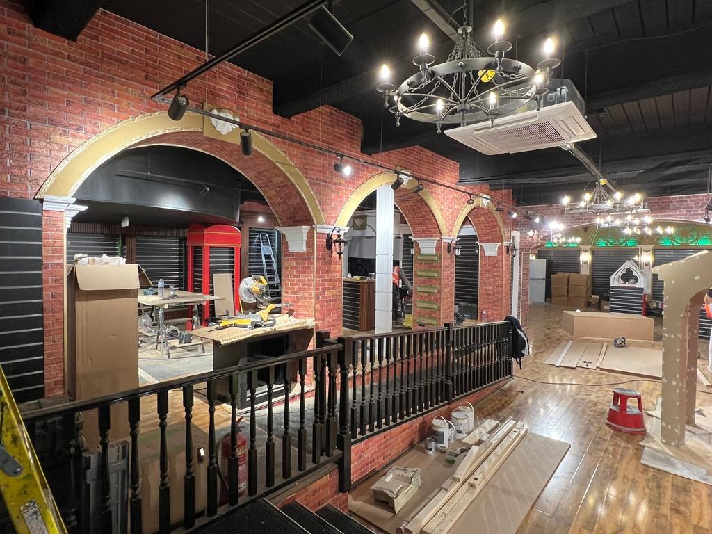 Brick archways and cast cornices under construction inside a themed retail shopfit.