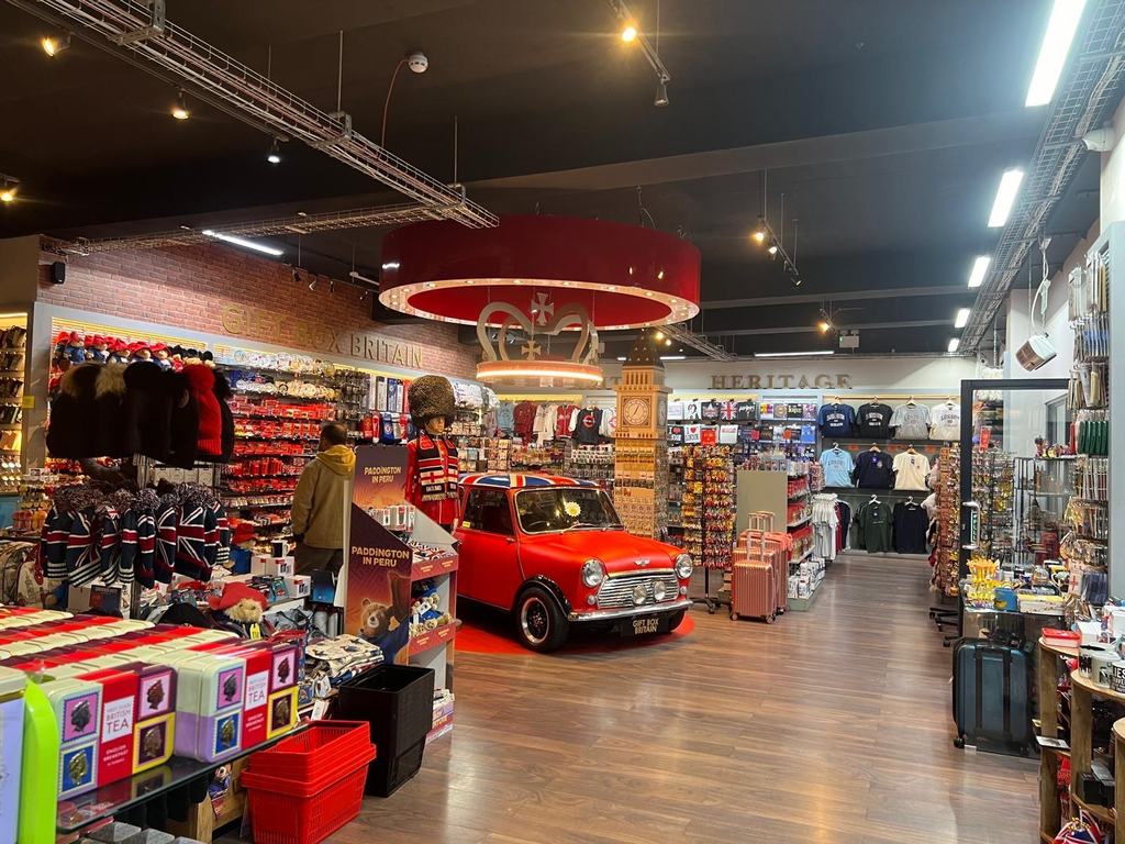 Interior of the completed Gift Box Britain store: brick-faced walls, an illuminated crown pendant and a red Mini set into the shop floor as a display plinth.