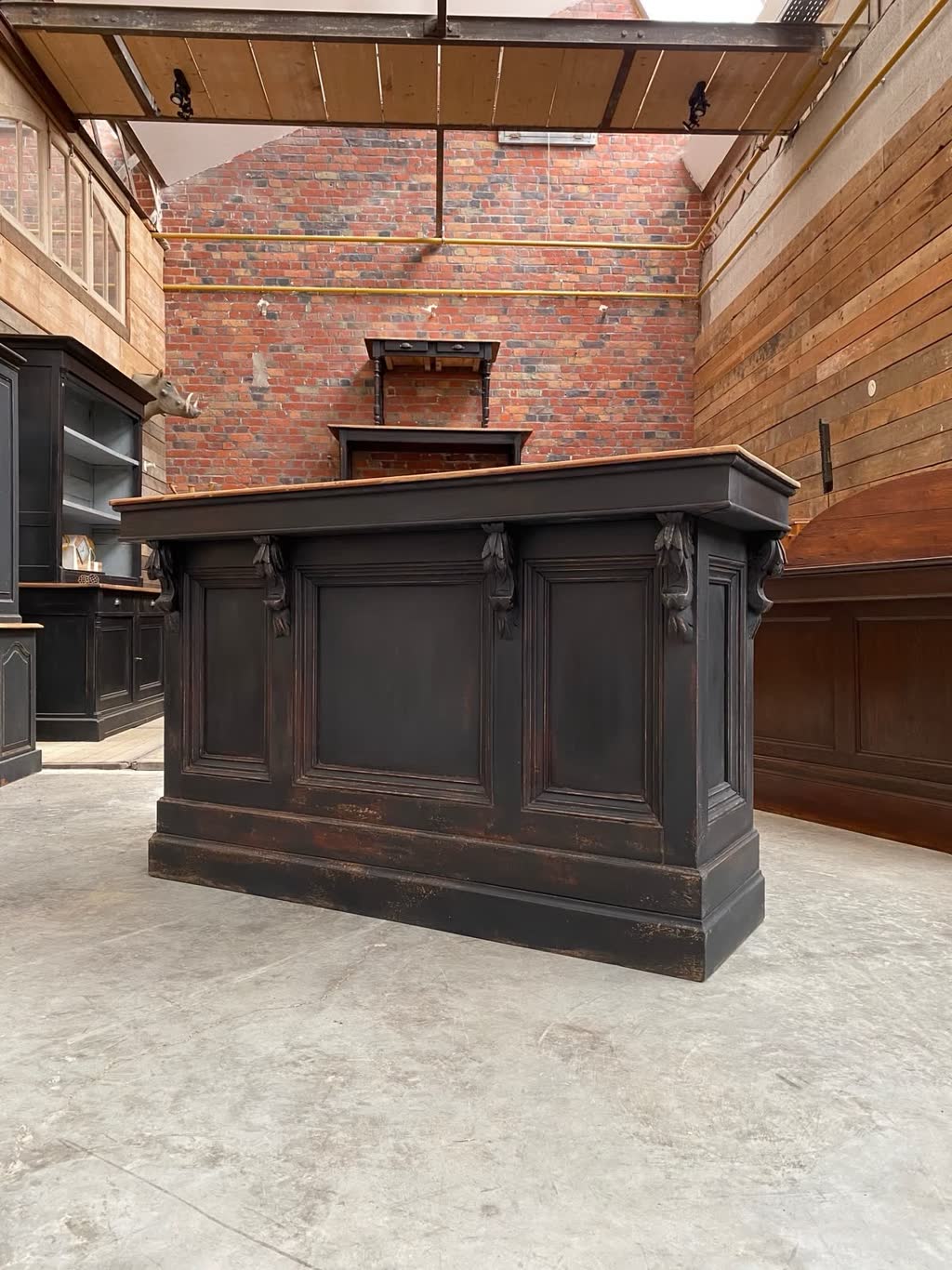Black painted panelled counter with carved corbels, standing in the workshop.